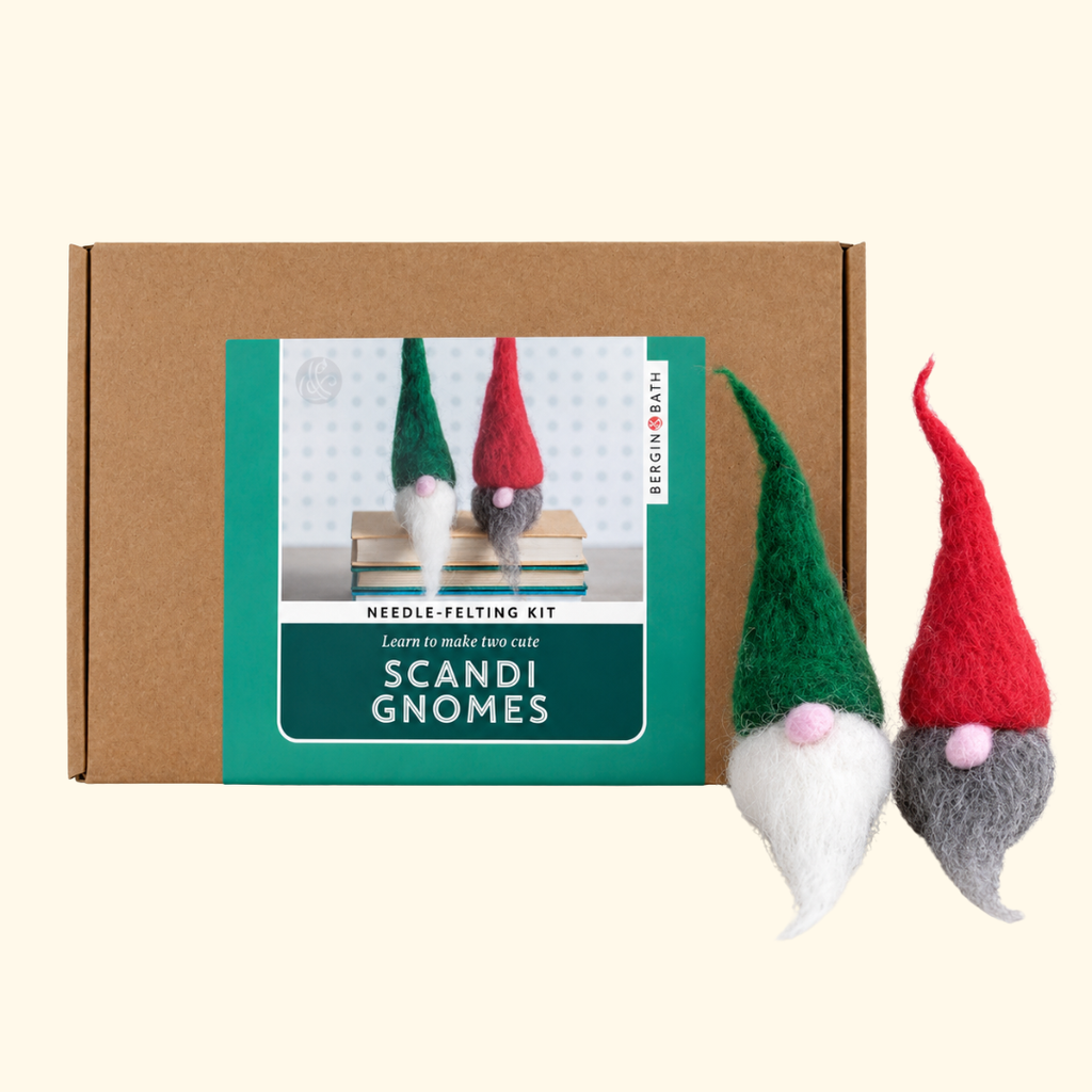 Bergin And Bath Scandi Gnomes Needle Felting Kit packaging displayed alongside two finished wool gnomes wearing red and green pointed hats.