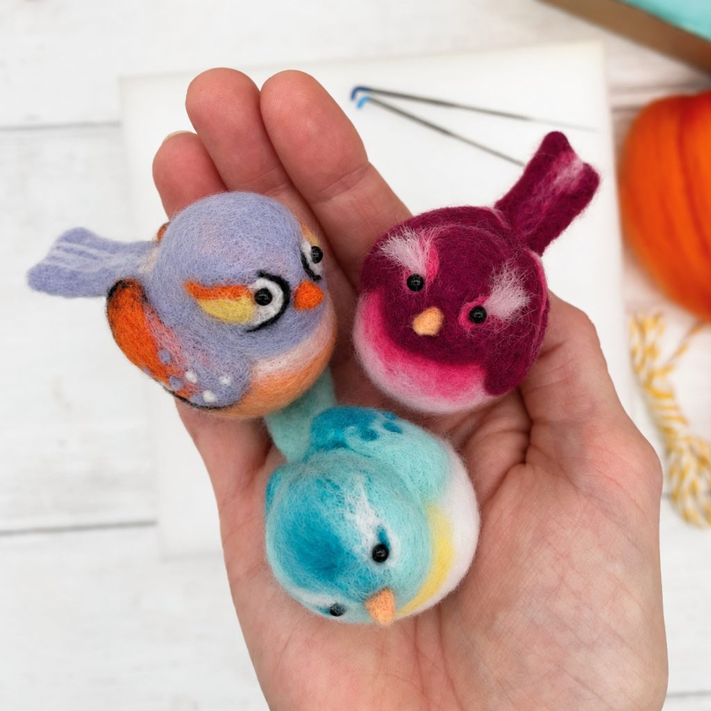 Three finished needle felted baby bird decorations held in one hand