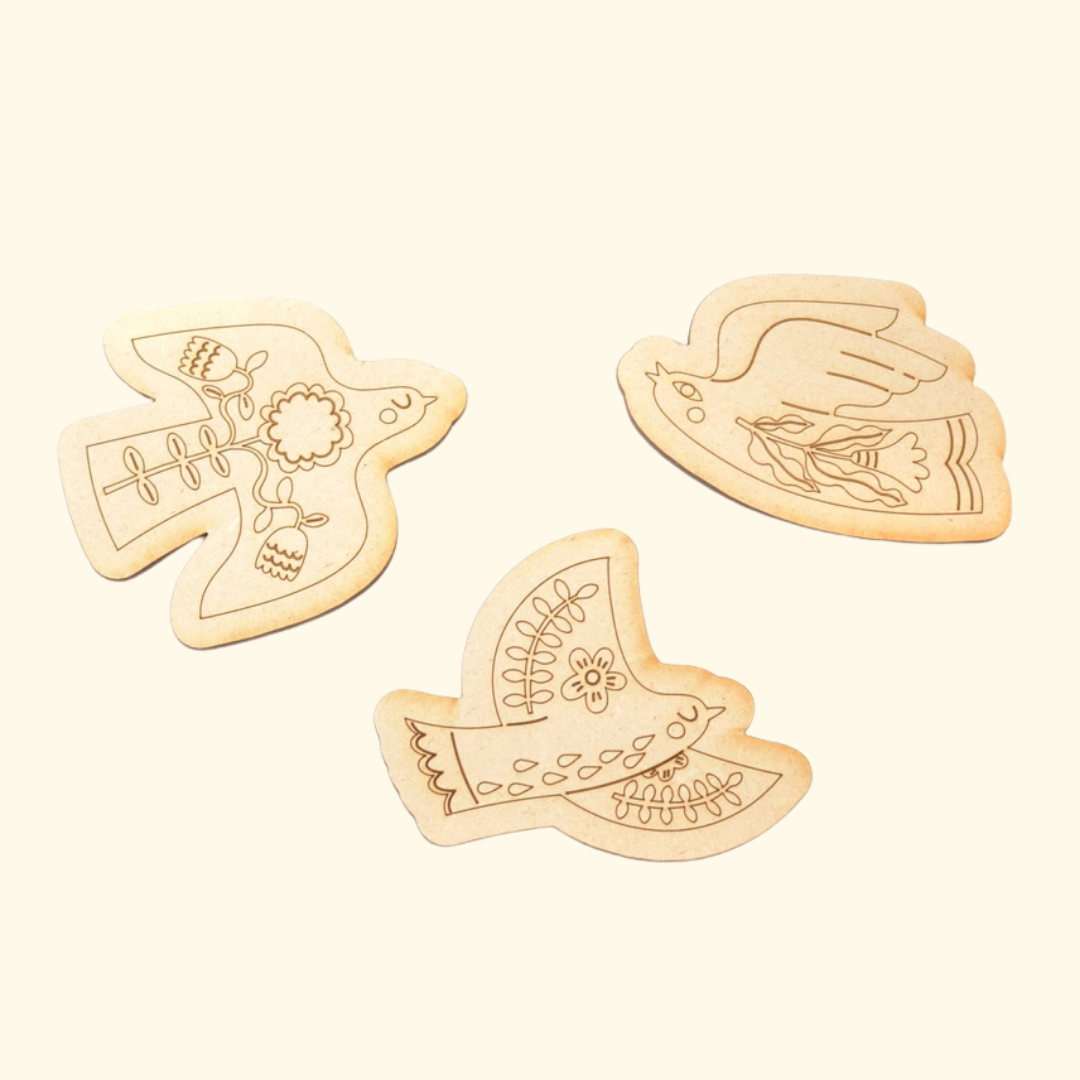 Three unpainted laser-cut wooden folk birds from the paint-your-own magnets kit.