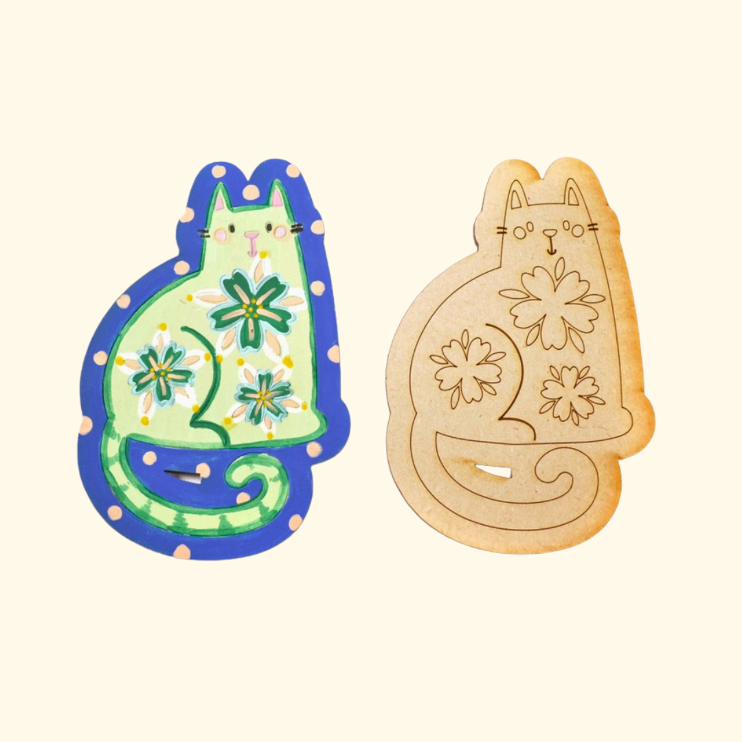 Painted green folk cat magnet beside an unpainted wooden cat design.