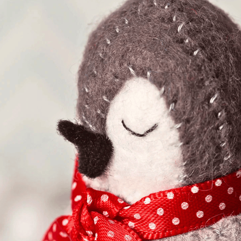 Close-up of a handmade felt penguin wearing a red polka dot scarf from the Set of 3 Penguin Felt Craft Kit.