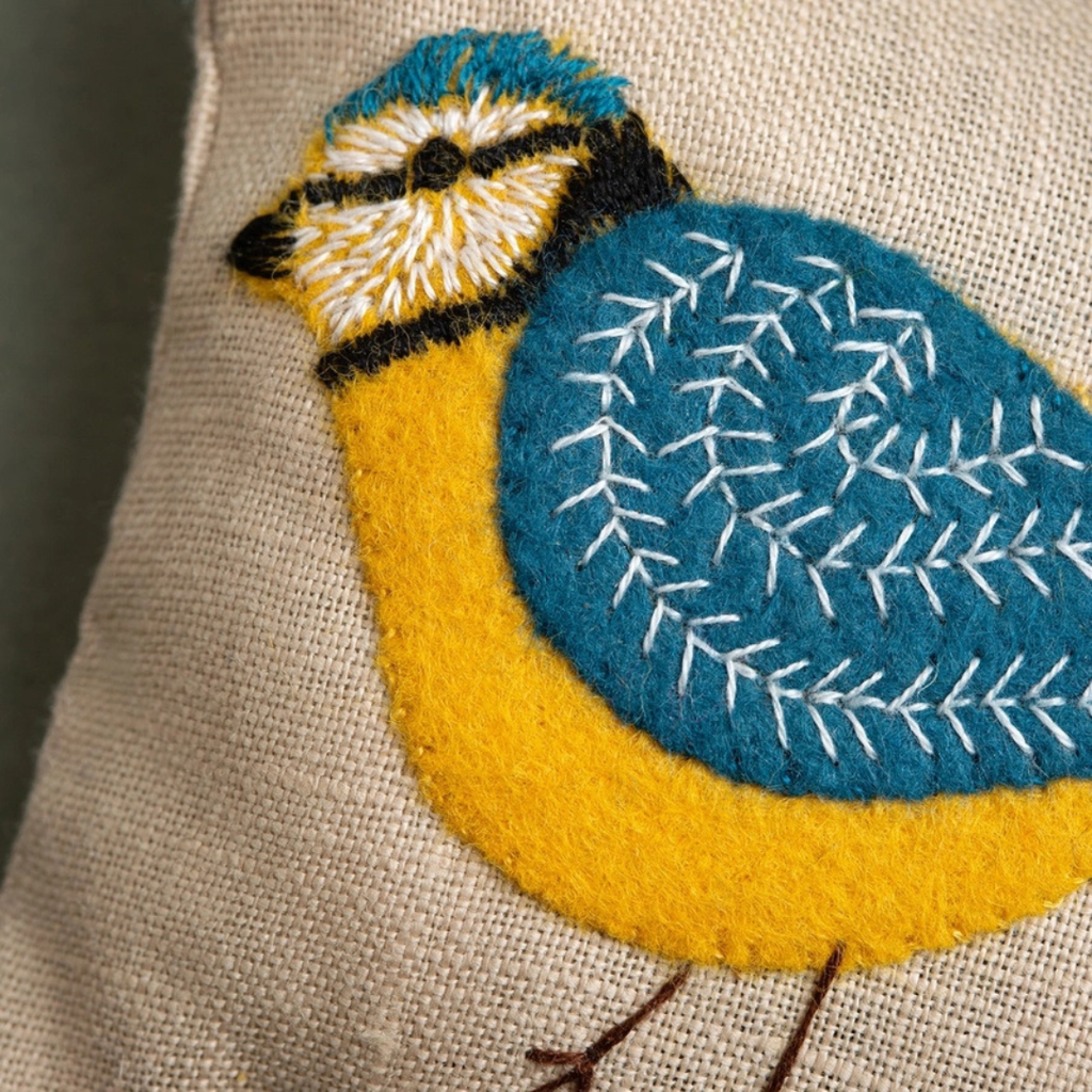 Close-up of the linen lavender bag featuring a colourful hand-embroidered blue tit with detailed blue and yellow stitching.