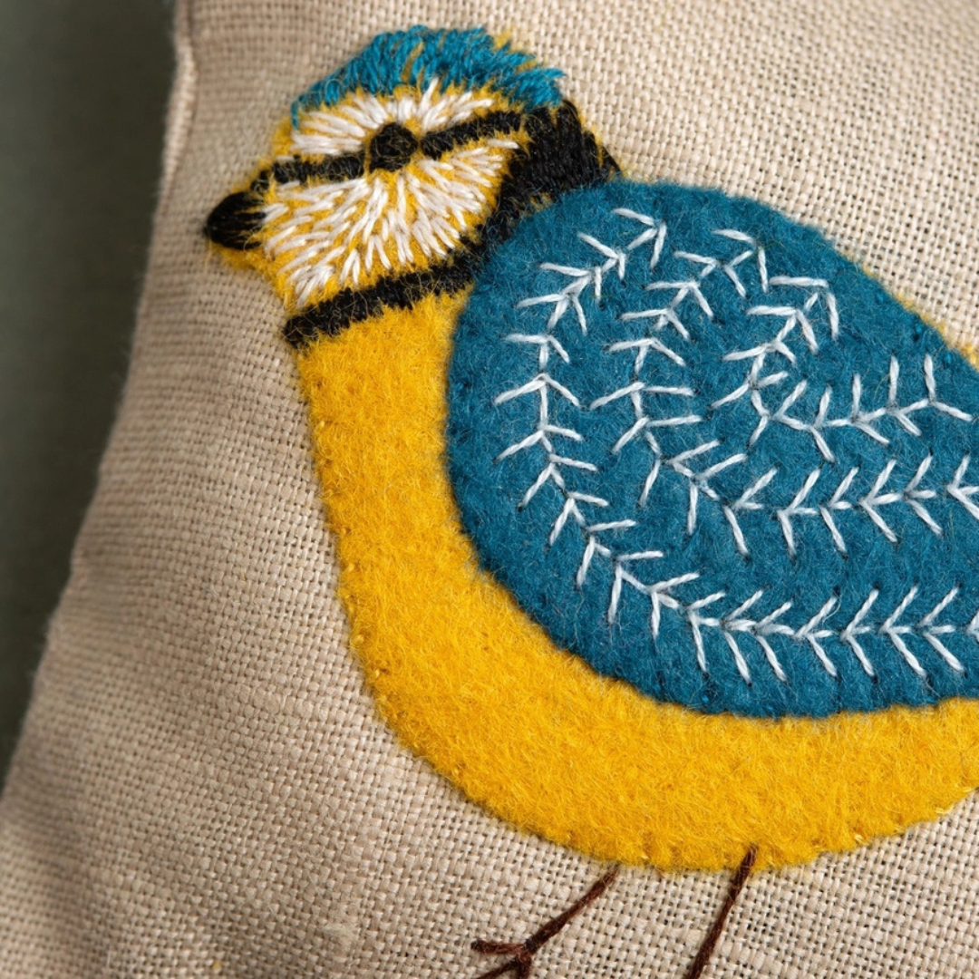 Close-up of the linen lavender bag featuring a colourful hand-embroidered blue tit with detailed blue and yellow stitching.