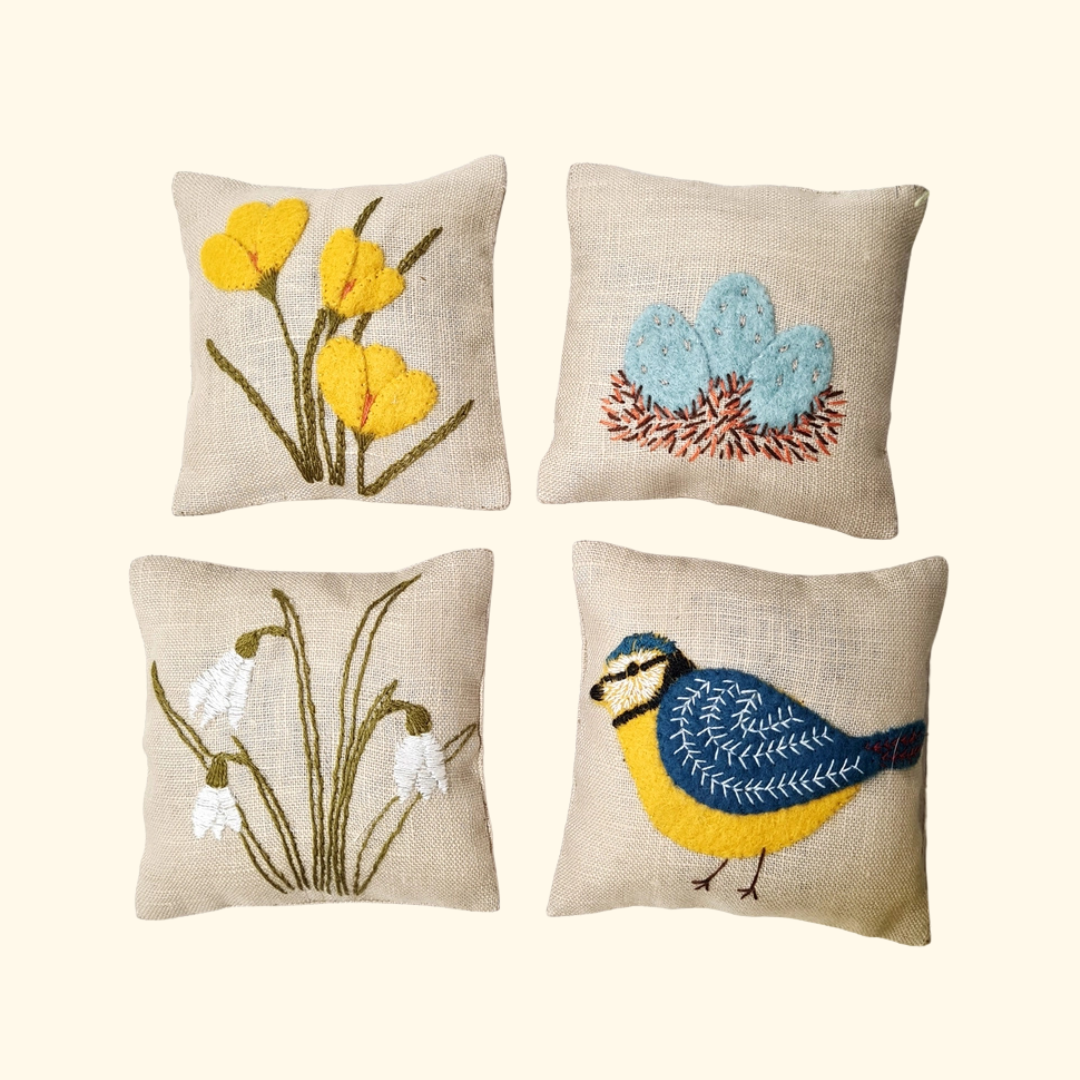 Completed set of four embroidered linen lavender bags featuring daffodils, a blue tit, a feather and delicate botanical designs.