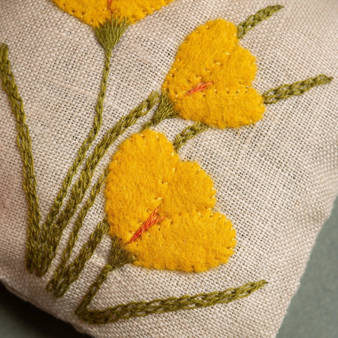 Close-up of the linen lavender bag featuring hand-embroidered yellow daffodils with green stems and leaves.