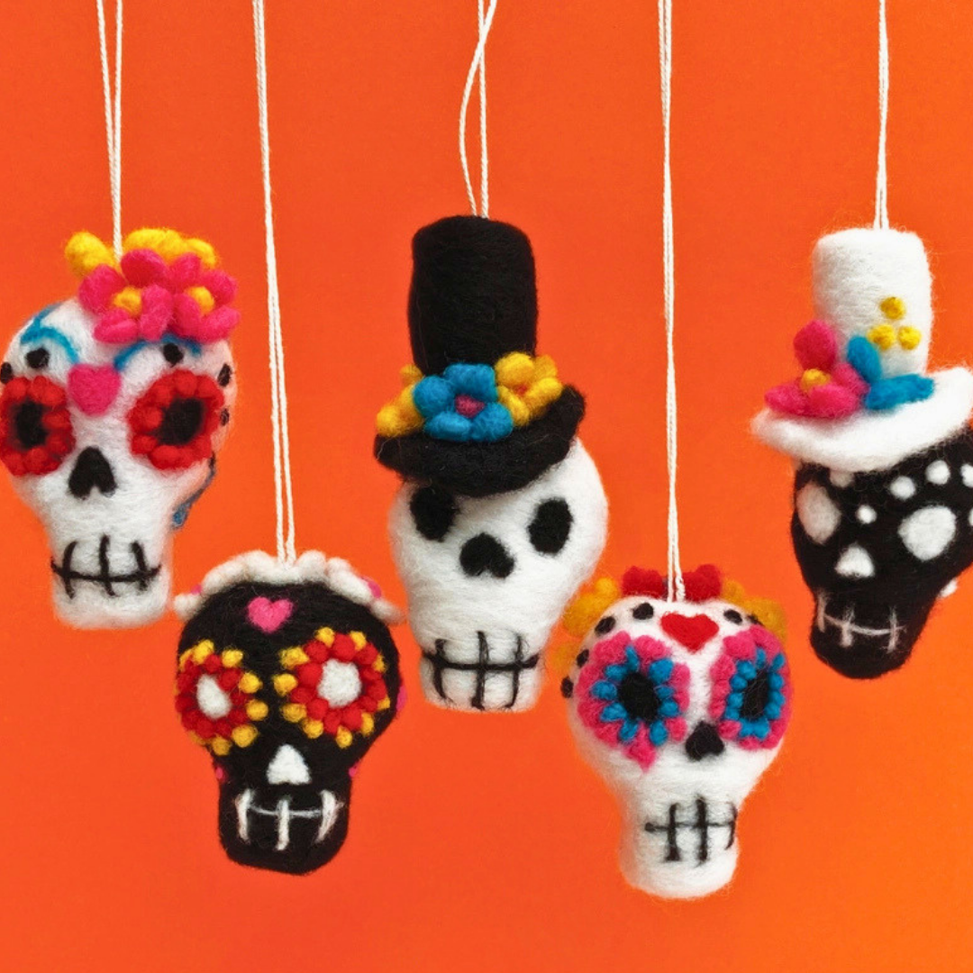 Five hanging needle felted sugar skull decorations on an orange background
