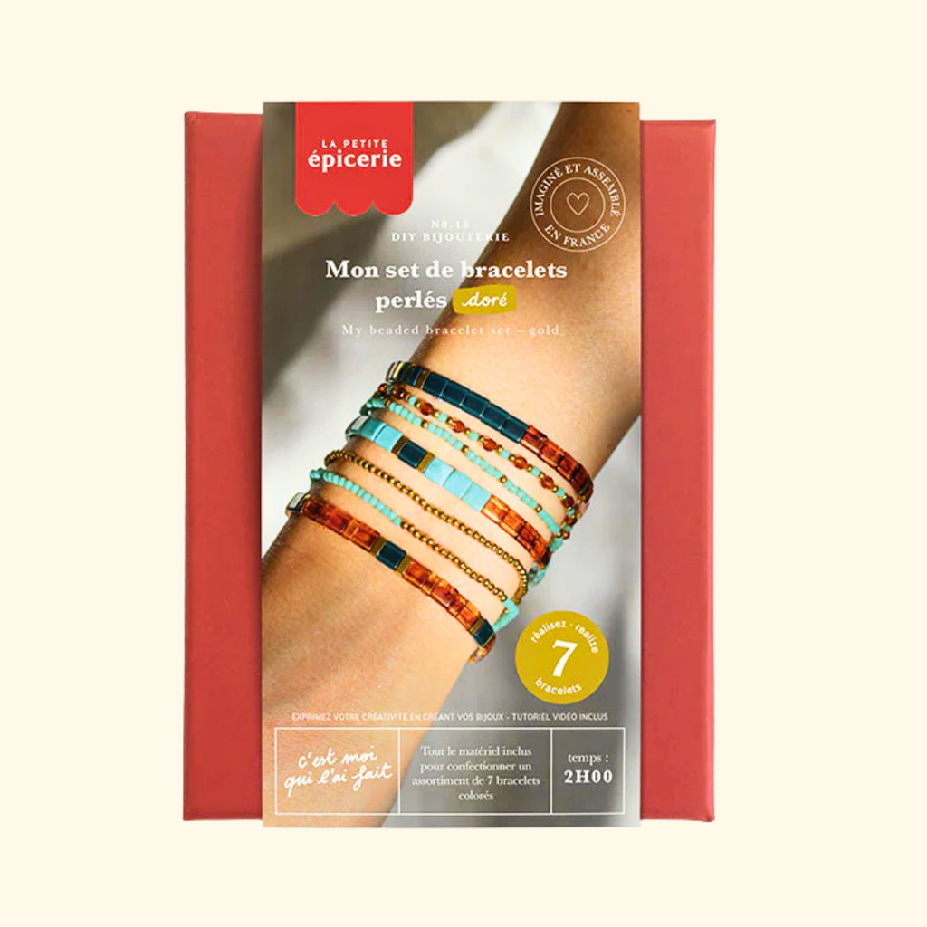 A DIY bracelet kit box from La Petite épicerie. The packaging features a red border, a central photo of a person's arm wearing colorful handmade beaded bracelets, and French text including 'Mon set de bracelets perles dor' and 'My beaded bracelets gold'.