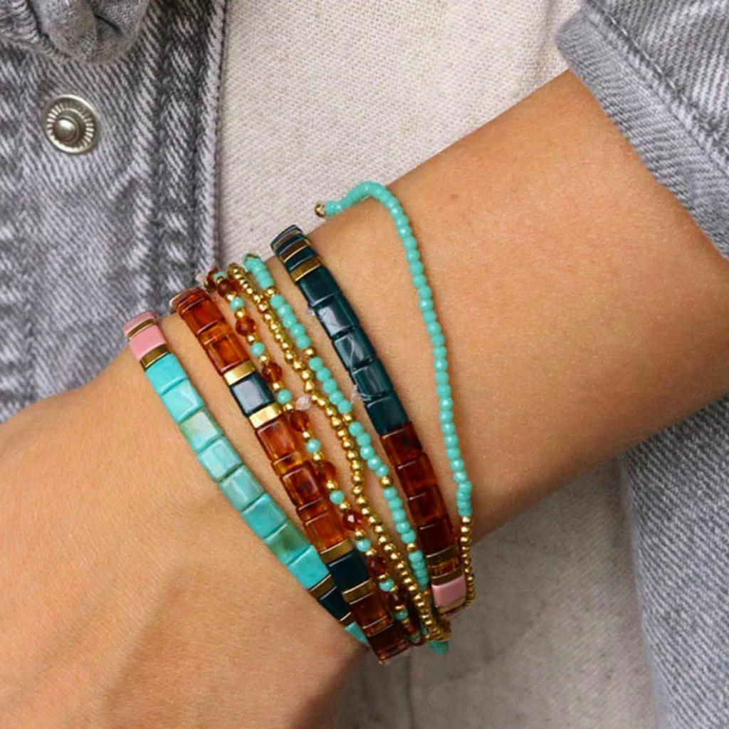 Hand wearing colourful beaded bracelets made with the La Petite Epicerie Set Of 7 Bracelet Making Kit.