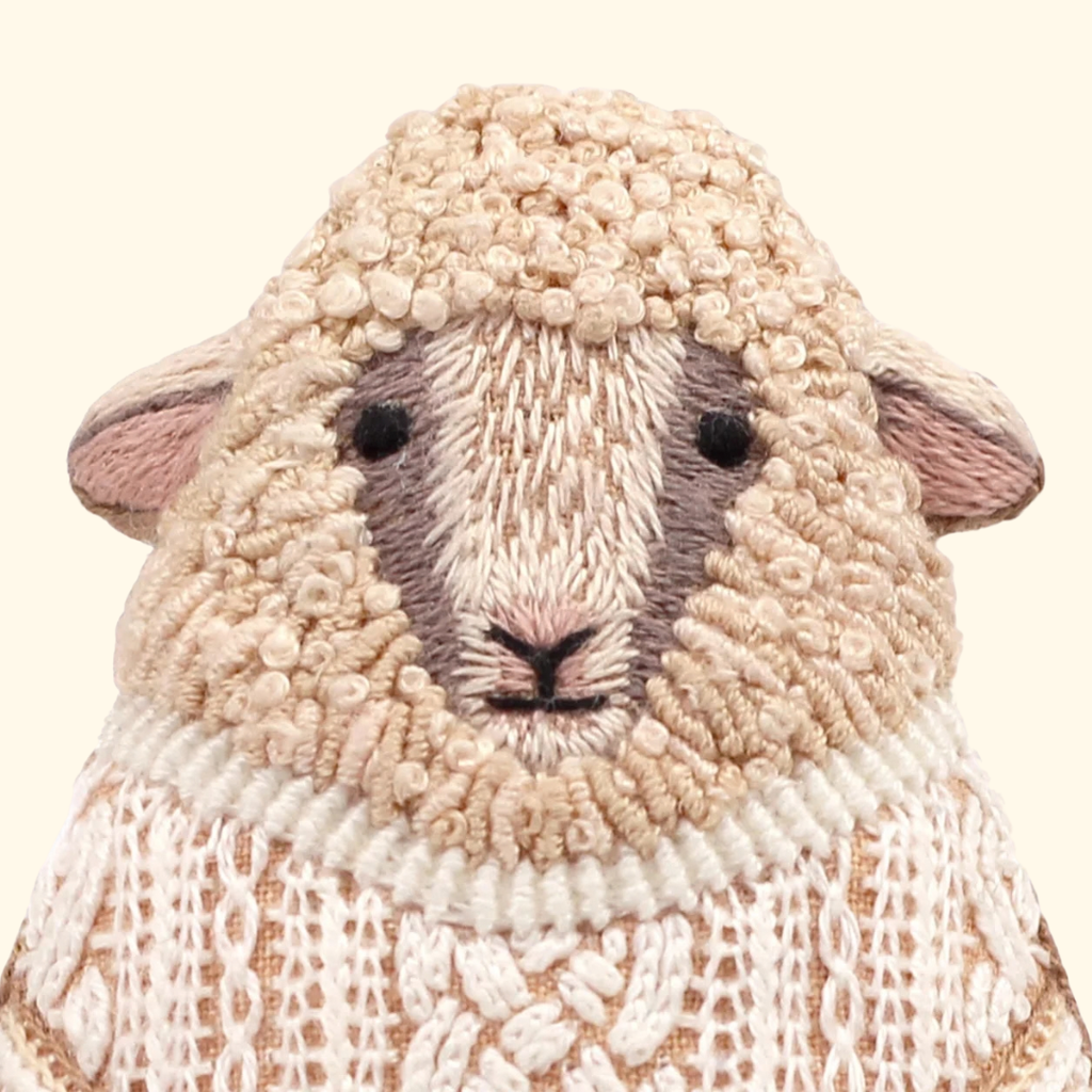 Close-up of the finished Kiriki Press Sheep Embroidery Kit, showing the sheep’s embroidered face, textured cream stitching and pink ears.