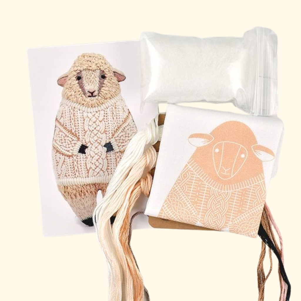 Kiriki Press Sheep Embroidery Kit with the finished sheep doll, embroidery materials and illustrated kit packaging.
