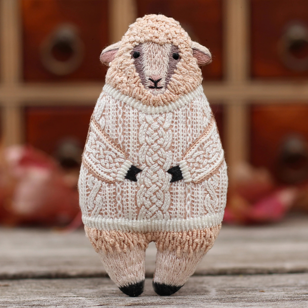 Finished Kiriki Press Sheep Embroidery Kit displayed standing on a wooden surface in a warm indoor setting.