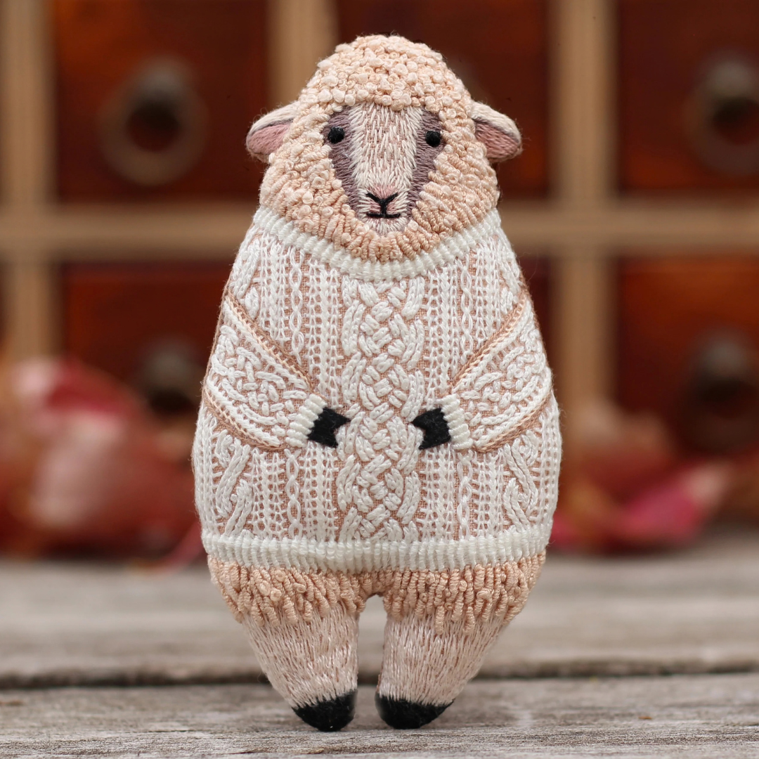 Finished Kiriki Press Sheep Embroidery Kit displayed standing on a wooden surface in a warm indoor setting.