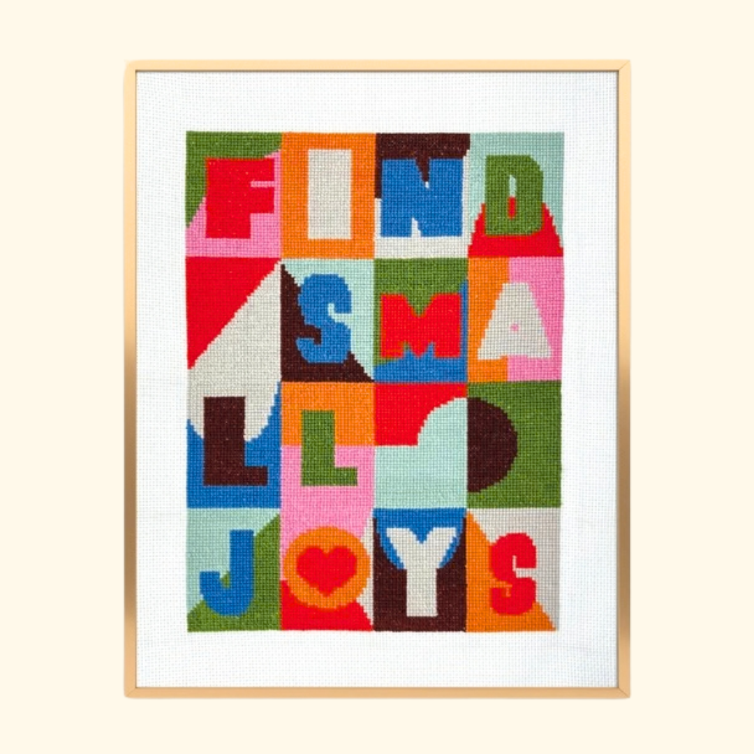 Small Joys Cross Stitch Kit by Budgiegoods, completed colourful typography design framed in light timber.