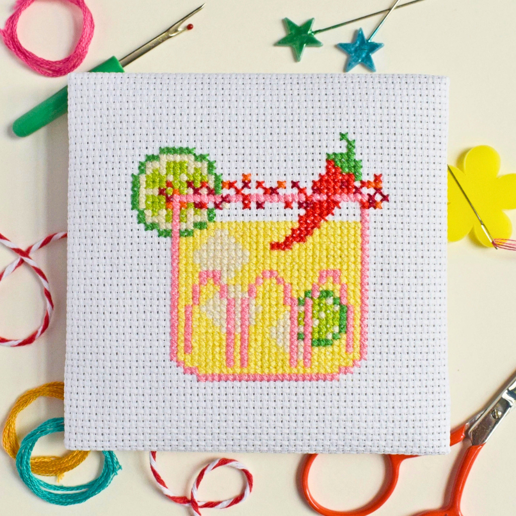 Completed spicy margarita cross stitch design styled on a red and white striped craft table.
