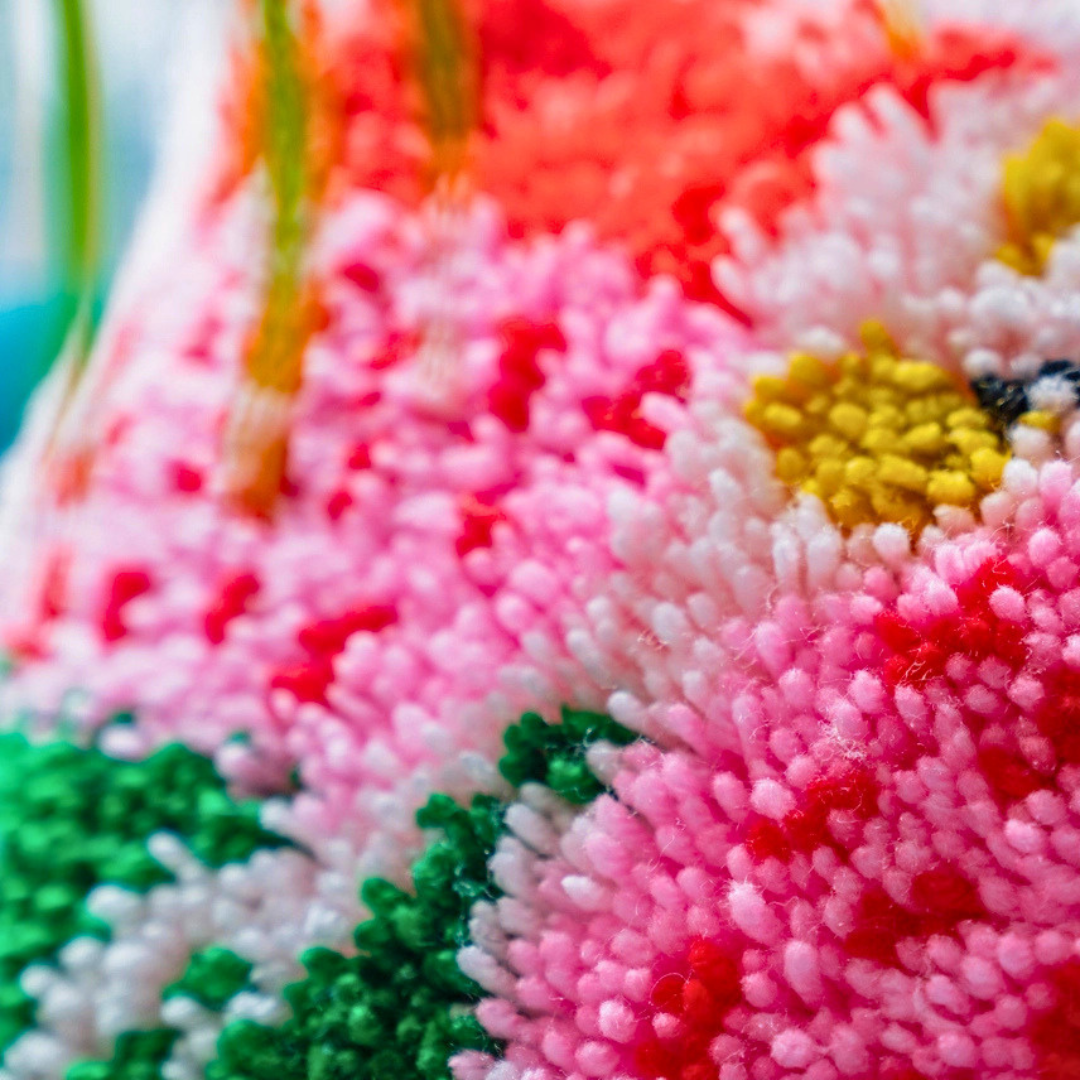 Close-up of the completed Sugarbush latch hook cushion showing the textured yarn and floral details.