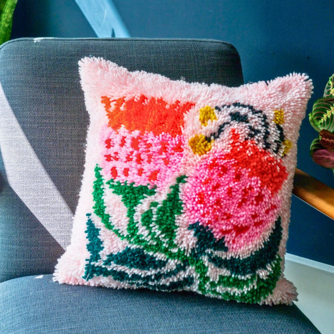 Completed Sugarbush latch hook cushion displayed on a chair, showcasing the finished floral design.