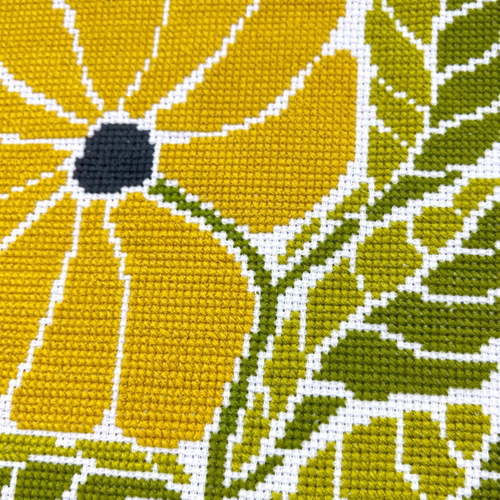 Close up of the Sunny Blossom Grid cross stitch showing textured stitches and bold yellow flower details on a geometric background.