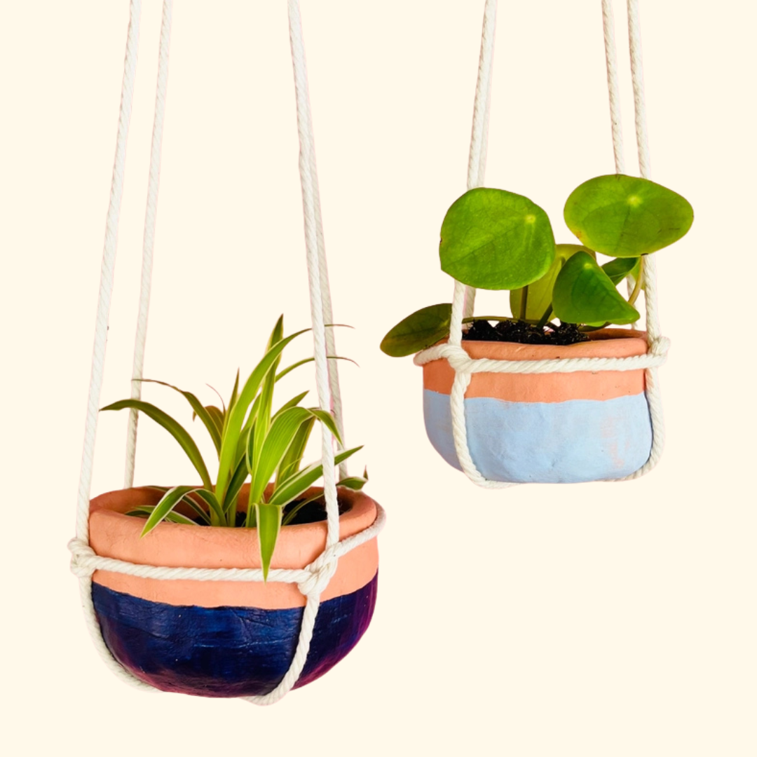 Finished handmade terracotta planter hanging from natural cord with a small indoor plant.
