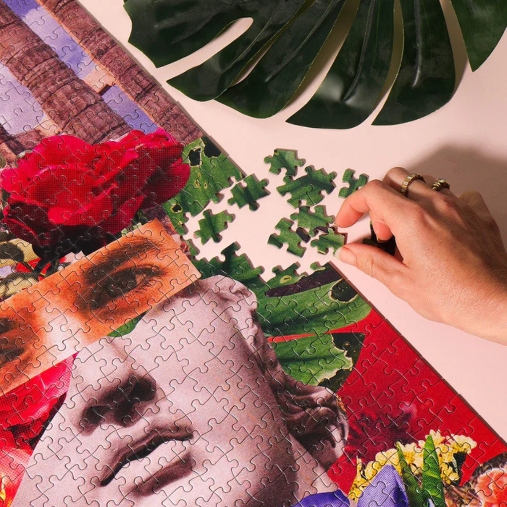 Detailed section of The Lovers 1000 piece puzzle featuring roses, classical sculpture and tropical leaves.