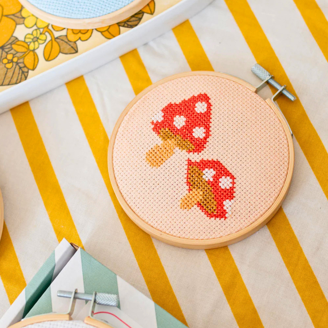 Finished toadstools cross stitch displayed in a bamboo embroidery hoop.