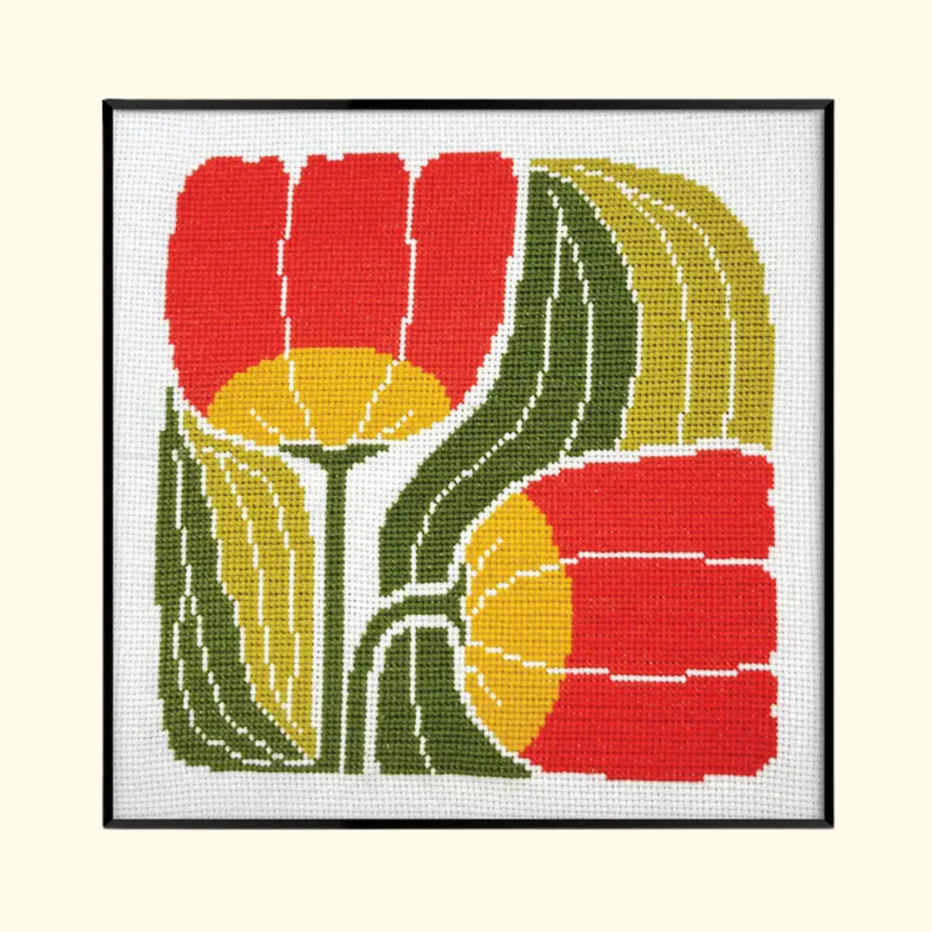 Completed Twin Blooms Grid Cross Stitch Kit by Budgiegoods featuring bold red and yellow flowers with curved green leaves.