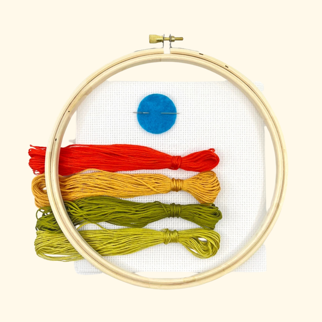 Twin Blooms Grid Cross Stitch Kit by Budgiegoods with embroidery hoop, colourful threads, white Aida fabric and needle.