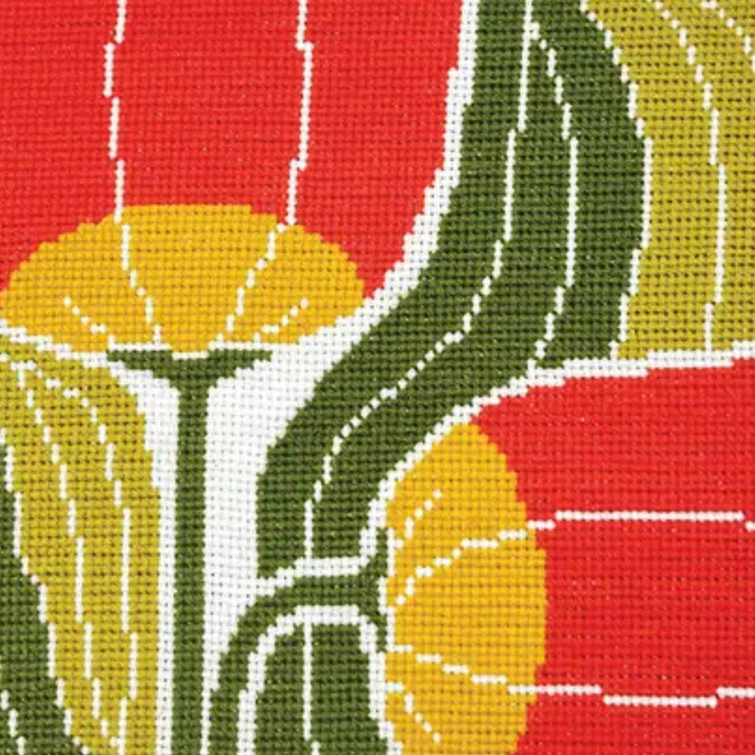 Close-up of the Twin Blooms Grid cross stitch design showing red and yellow flowers with textured green leaves.