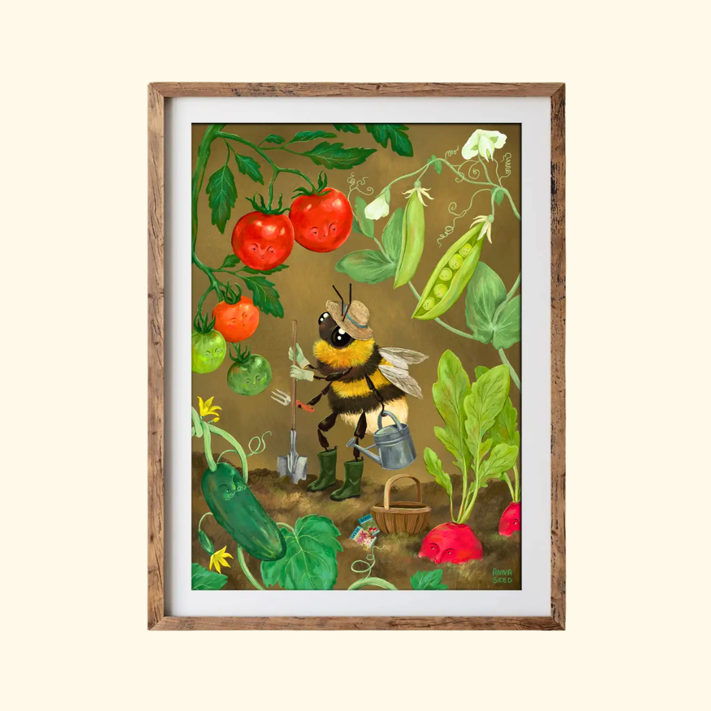 Veggie Patch A4 art print by Anna Seed Art displayed in a timber frame, featuring a bumblebee working among colourful vegetables and garden plants.
