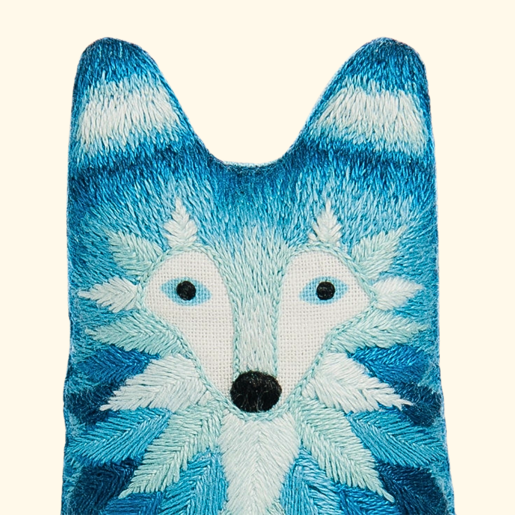 Close-up of the finished wolf embroidery doll featuring textured blue and white stitching.