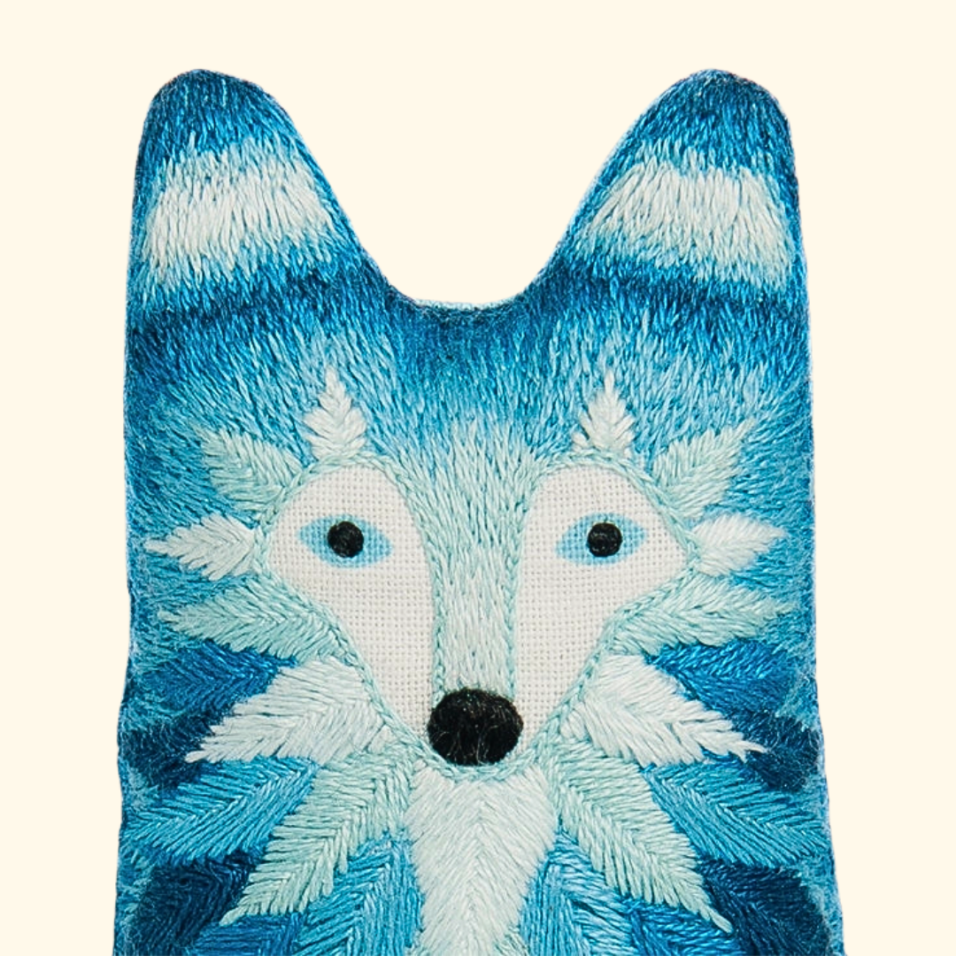Close-up of the finished wolf embroidery doll featuring textured blue and white stitching.