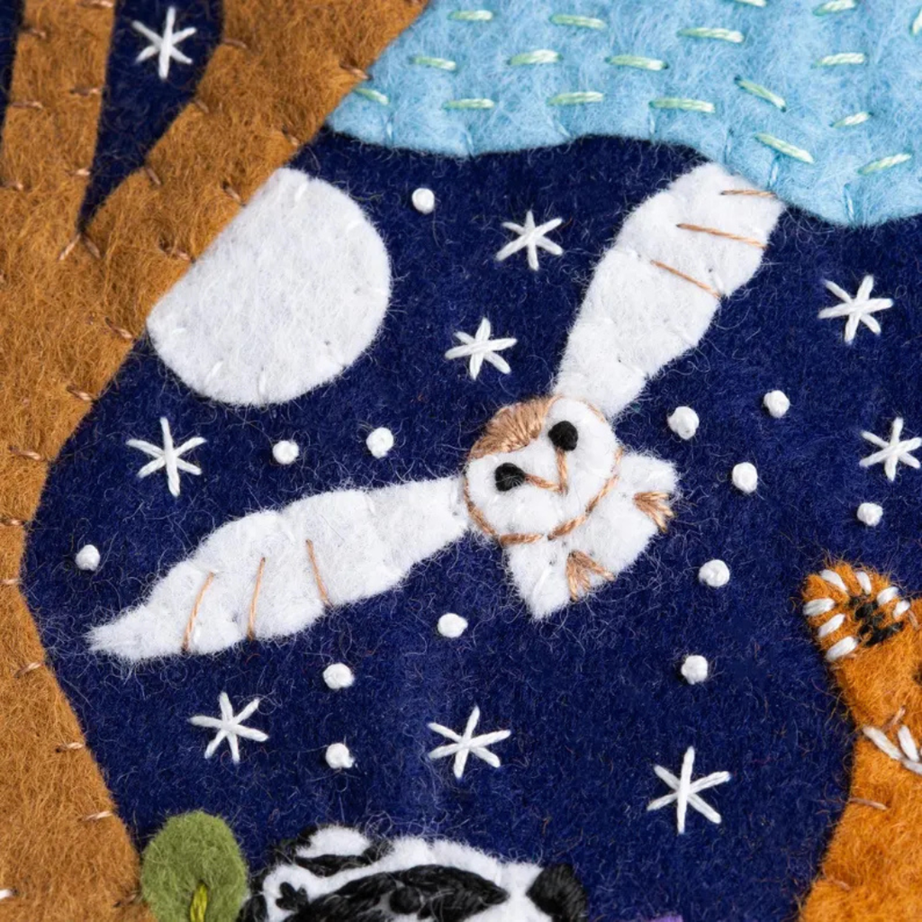 Close up of felt owl flying beneath a moon and stars on the woodland wall hanging design